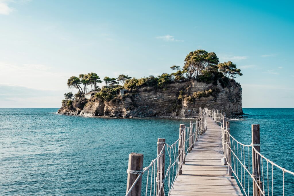 Blue and green island in an ocean with a walking bridge leading to it